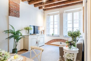 A cozy living room with a television, a dining table with a plant, and a sofa. - Paolino View Apartment (Lucca)