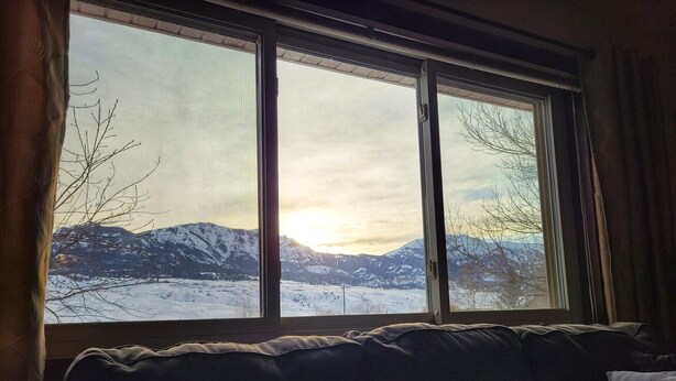 Ein Zimmer mit einem großen Fenster mit Blick auf eine verschneite Berglandschaft.