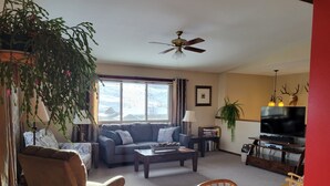 Ein Wohnzimmer mit Sofa, Sessel, Couchtisch, TV-Schrank und Esstisch.