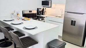 A modern kitchen with a central island, stainless steel appliances, and a contemporary light fixture.