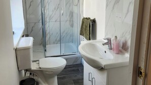 A modern bathroom with a toilet, shower, and sink.