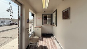 A hallway with a bench, a 'WELCOME' sign, a 'ICE' cooler, and a view of parked vehicles outside.