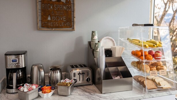 A breakfast setup with a coffee maker, toaster, and a fruit and bread display.