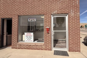 A brick building with a large window displaying a 'Rooms Available' sign and a 'Welcome' sign. - Sands Inn Rock Springs Near I-80 (Rock Springs)