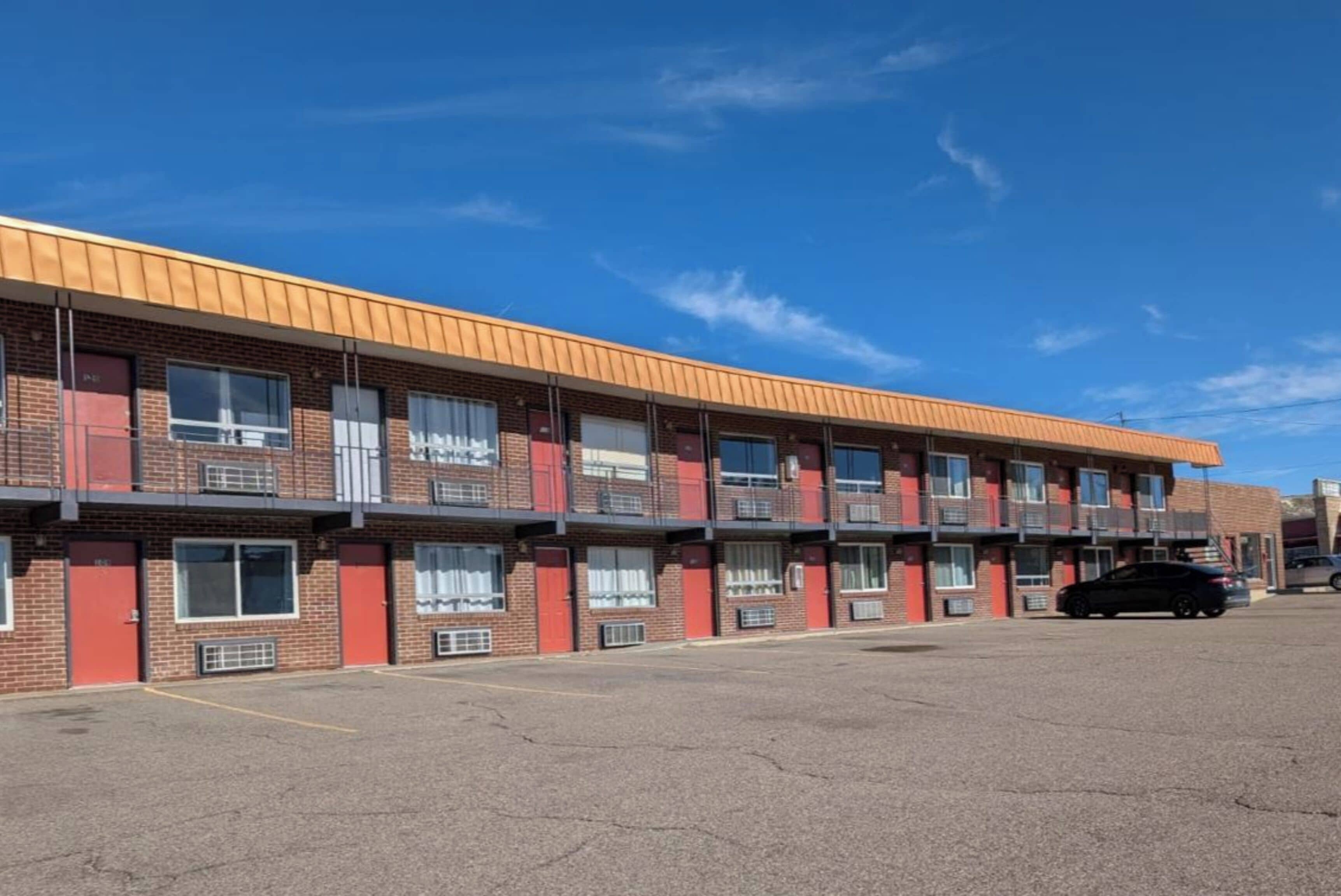 Un motel à plusieurs étages, avec une façade en briques, de nombreux balcons et un parking.