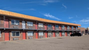 A multi-story motel with a brick facade, multiple balconies, and a parking lot.