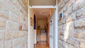 A stone-walled hallway leading to a room with a radiator, wooden flooring, and a door with a security device. - Morski dragulj by Interhome (Vodice)
