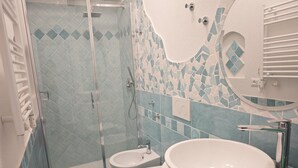 A bathroom with a glass shower enclosure, two sinks, and a toilet.