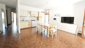Een moderne keuken met een eethoek, witte kasten en een flatscreen televisie.
