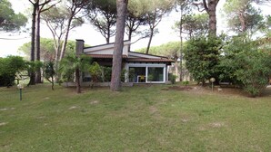 Ein Haus mit einem Ziegeldach, einem Steinkamin und einer Glastür, die auf eine überdachte Terrasse führt.