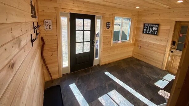 Un intérieur en bois avec une porte noire, une fenêtre et une enseigne sur le mur.