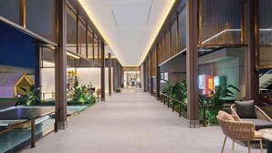 A modern hotel corridor with a glass railing, seating area, and plants. - Howard Johnson by Wyndham Life Kunming Guandu Hotel (Kunming)