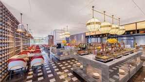 A modern hotel dining area with a long table and chairs, buffet stations, and a patterned floor. - Howard Johnson by Wyndham Life Kunming Guandu Hotel (Kunming)