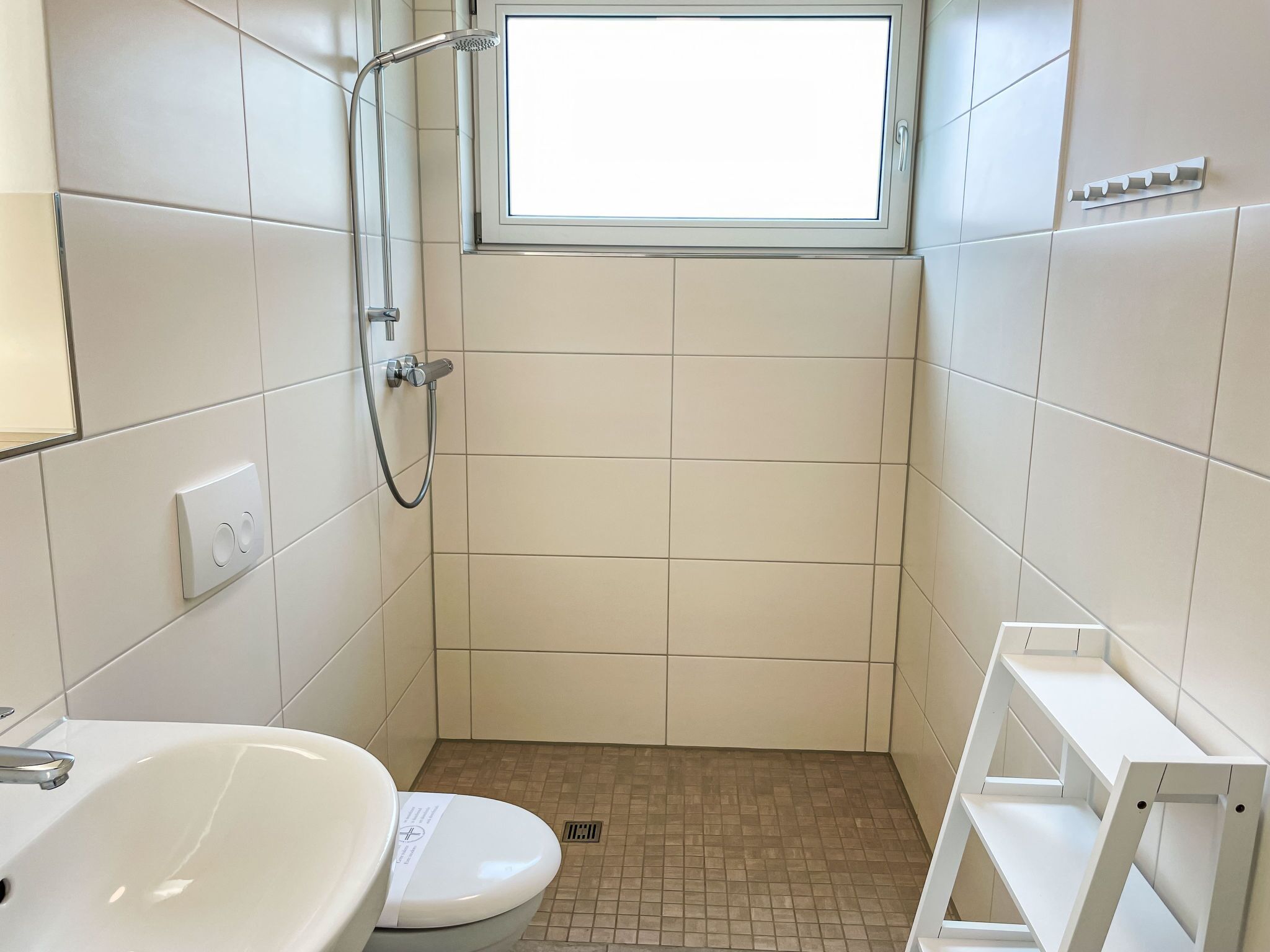 A small, modern bathroom with a toilet, a sink, and a shower.