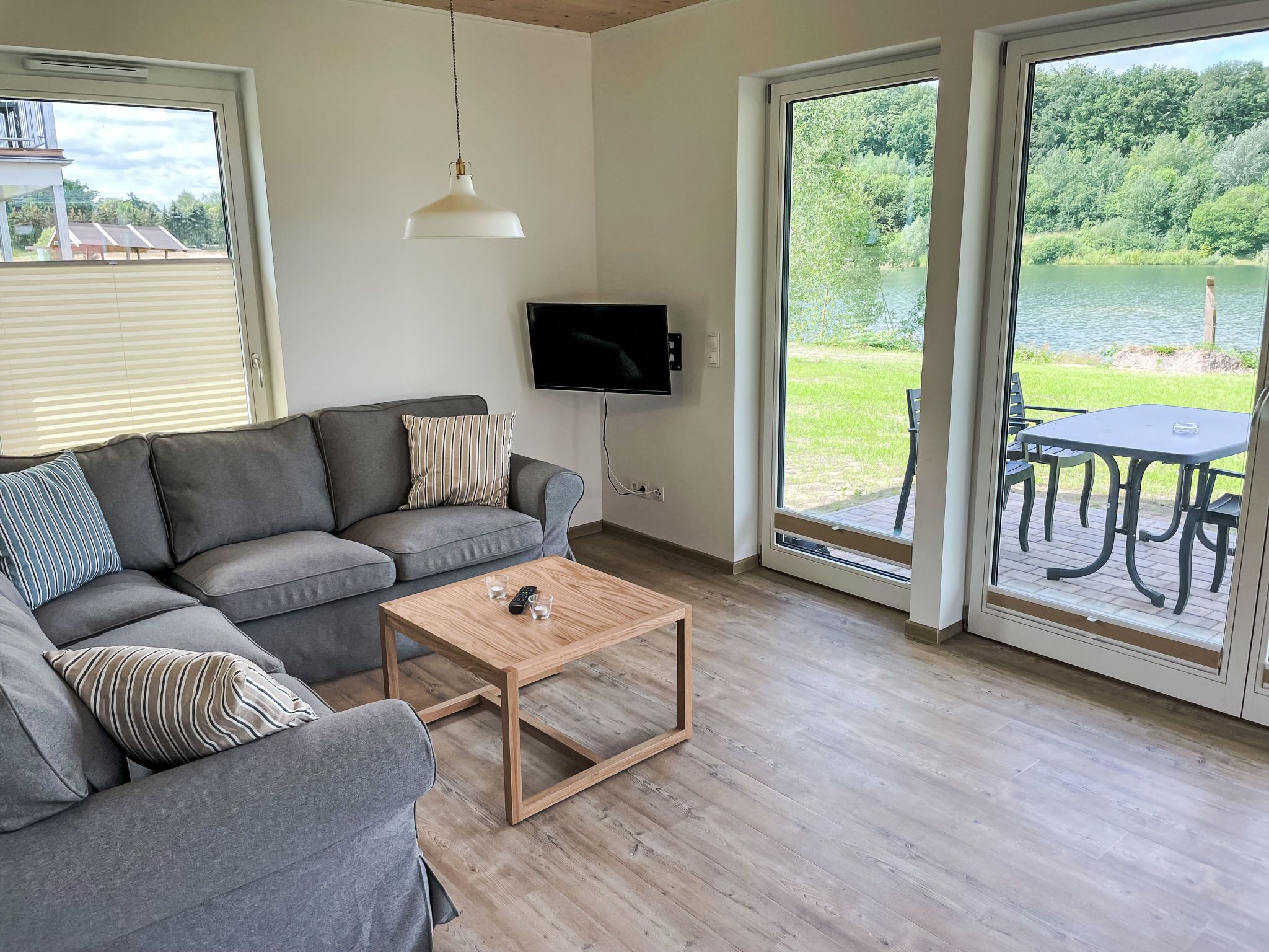 A modern living room with a grey sectional sofa, a wooden coffee table, and a TV mounted on the wall.