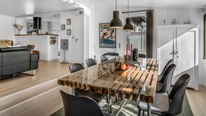 A modern dining area with a glass-top table, black chairs, and pendant lighting.