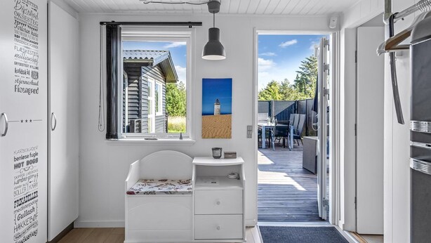 A modern kitchen with a white cabinet, a window with a view of a house, and a painting on the wall.