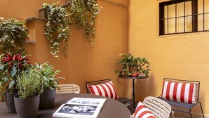 Un espacio al aire libre acogedor con una mesa redonda, cojines a rayas y plantas en macetas.