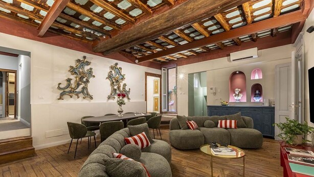 Un amplio salón con techo de madera, un comedor con mesa y sillas, y una cocina con armarios azules.