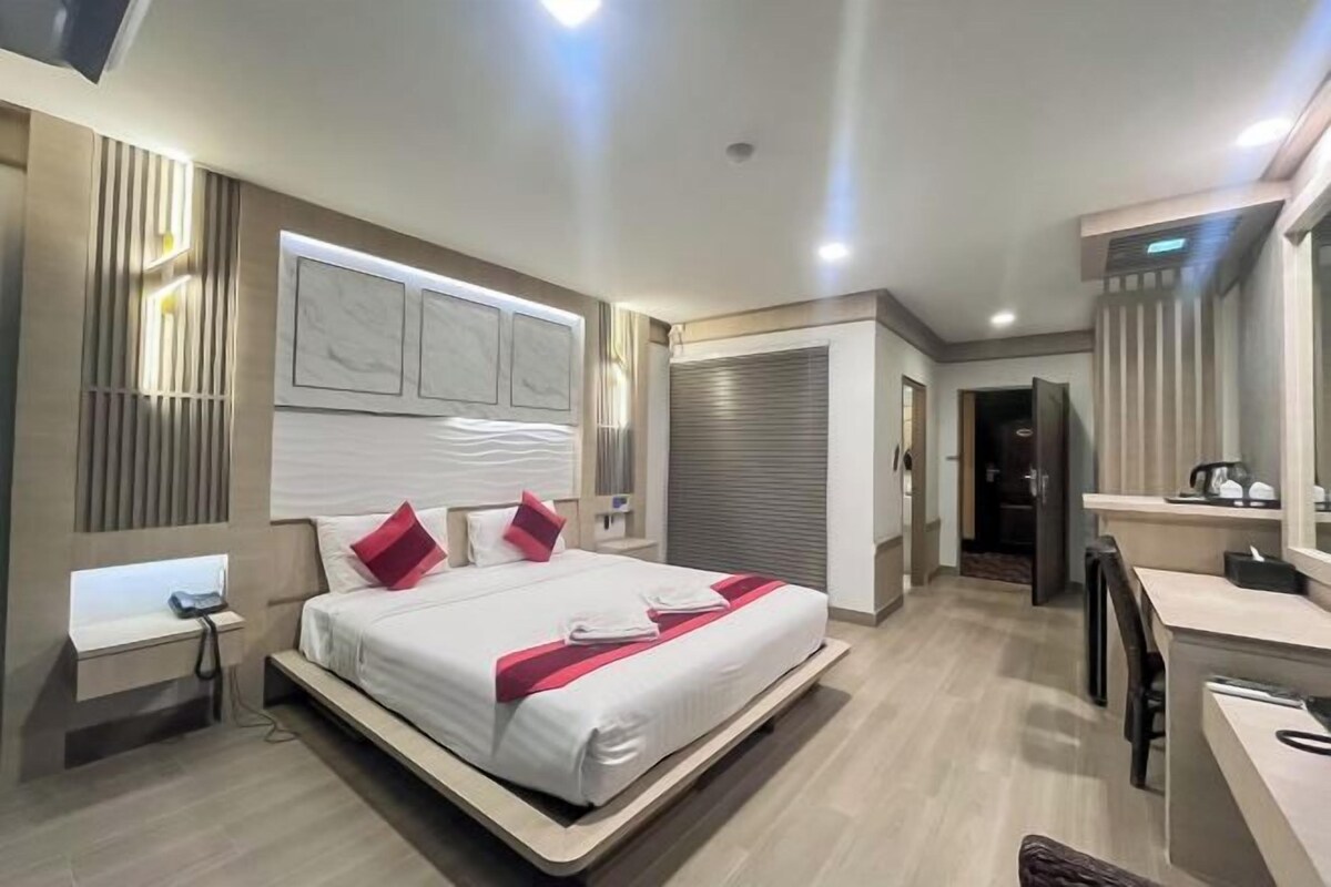 A modern hotel room with a large bed, bedside tables, a desk, and a chair.