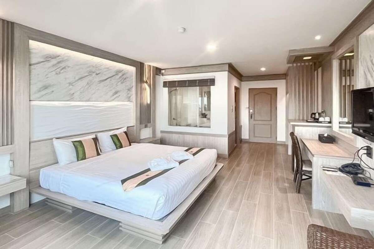 A modern hotel room with a large bed, a desk, and a television.