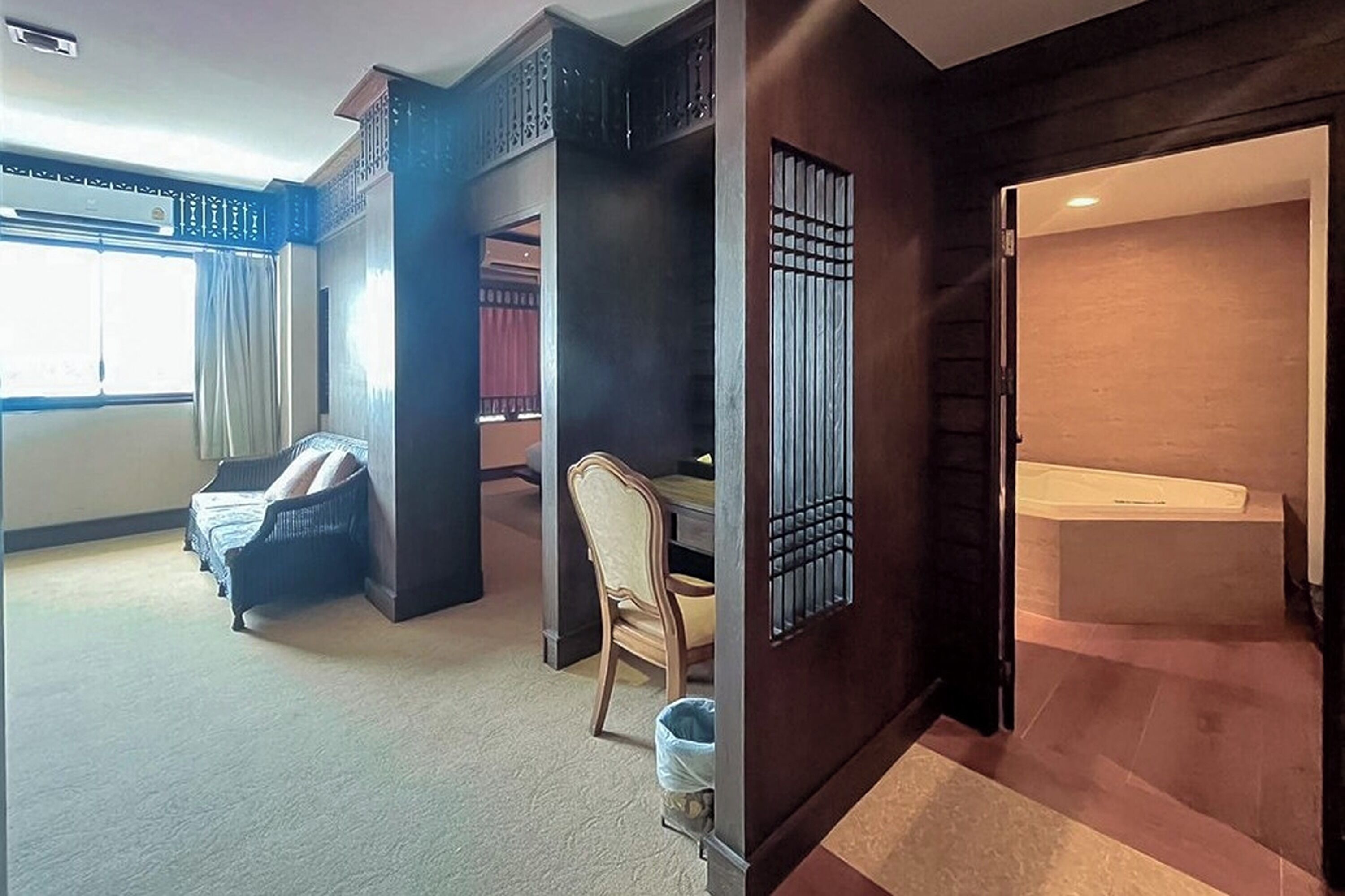 A room with a bed, a chair, a desk, and a window with curtains.