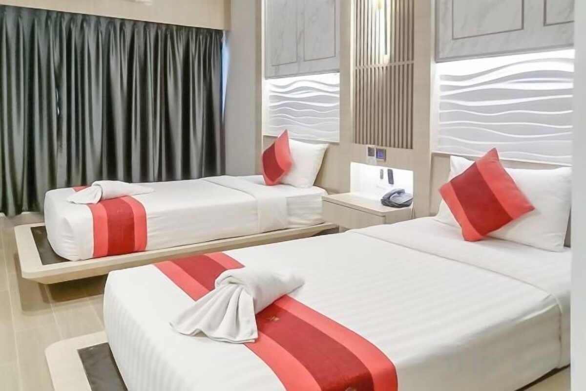 Two beds with red accents, a nightstand, a mirror, and a curtain.