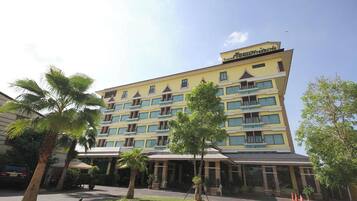 Un hotel de varios pisos con fachada amarilla, múltiples balcones y una zona de entrada cubierta.