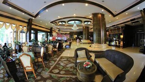 A spacious lobby with a central column, seating areas, and a chandelier. - Ruean Phae Royal Park Hotel (Phitsanulok)