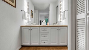 A bathroom with a vanity, double sinks, and a mirror with lights. There are three drawers and a towel rack. - Palisades Condo – Walk to Ski Lifts, Mtn Views (Tahoe City)