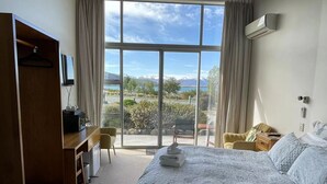 Una habitación de hotel con una cama grande, un escritorio, una silla y vistas al exterior.