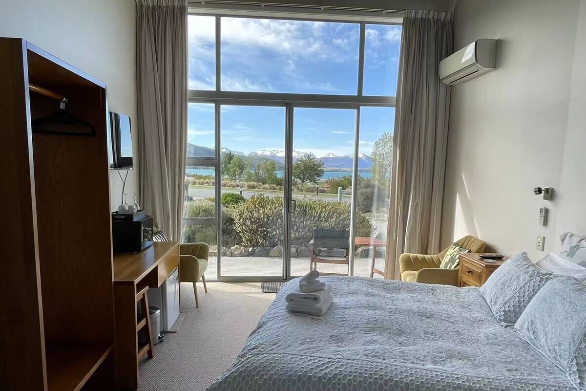 Une chambre d’hôtel avec un grand lit, un bureau, une chaise et une vue sur l’extérieur.