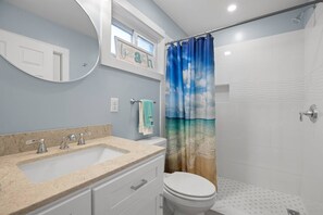 Ein Badezimmer mit Waschbecken, Toilette und Duschvorhang mit Strandmotiv.