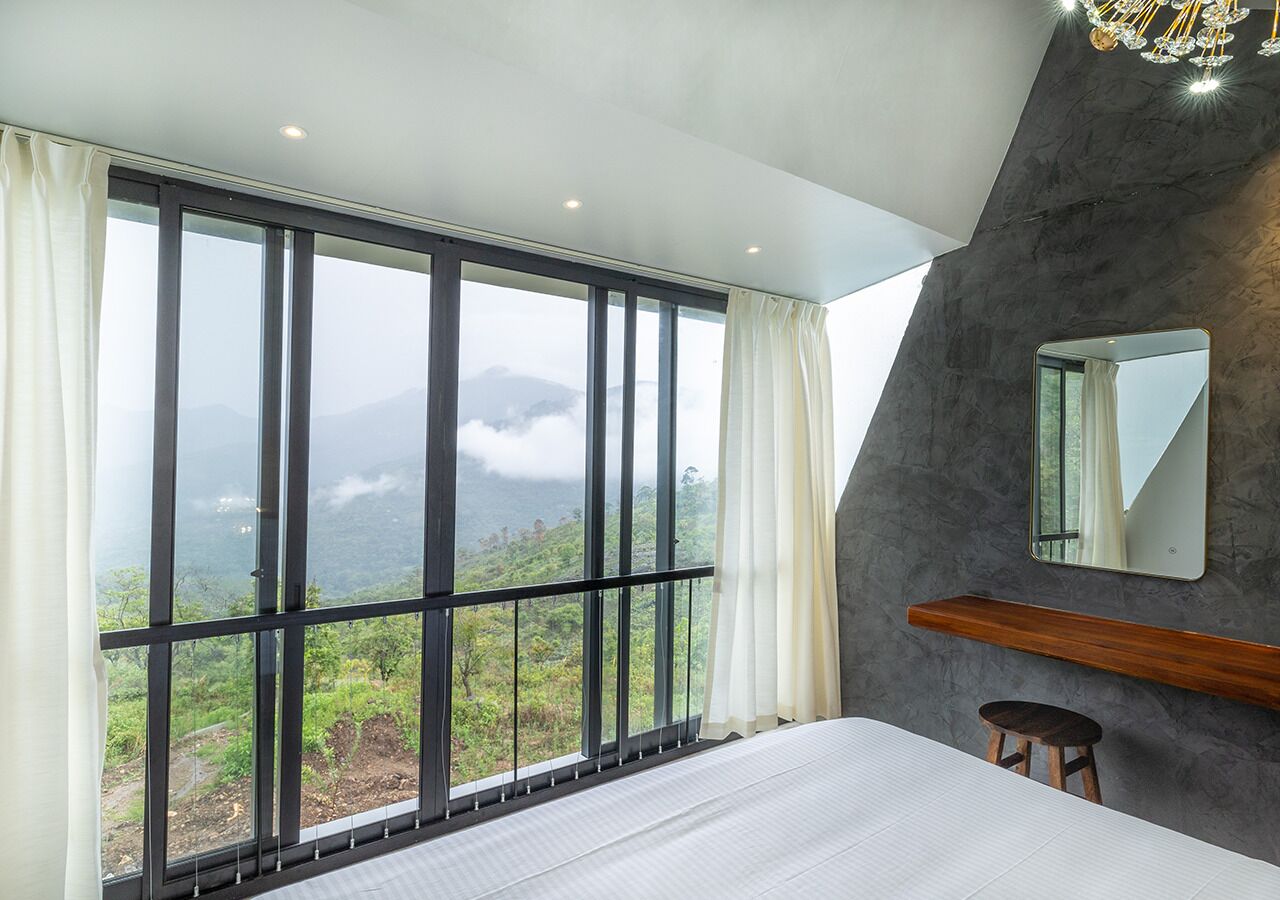 A bedroom with a large window offering a view of a mountainous landscape.