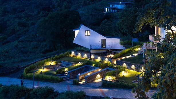 A modern house with a unique geometric design, surrounded by landscaped gardens and illuminated pathways. - TOMORROWLAND  FARMS AND SUITES (Kodaikanal)