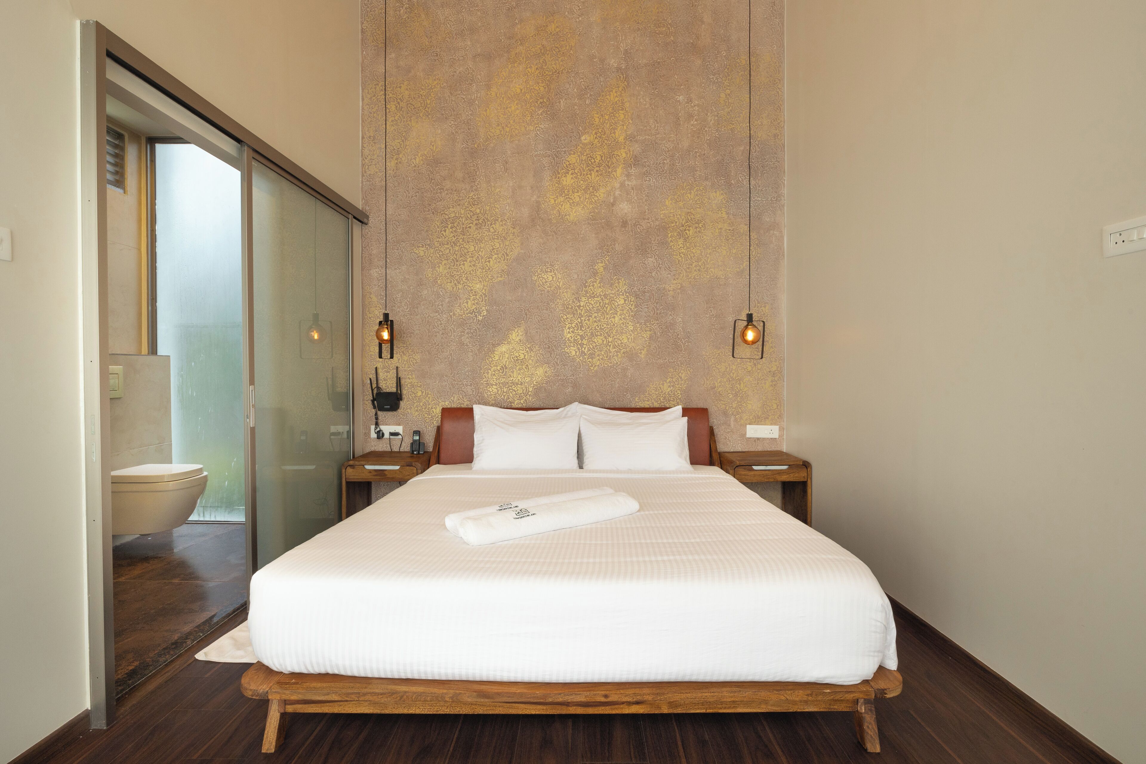 Een hotelkamer met een groot bed, een douchecabine van glas en een gestructureerde wand.