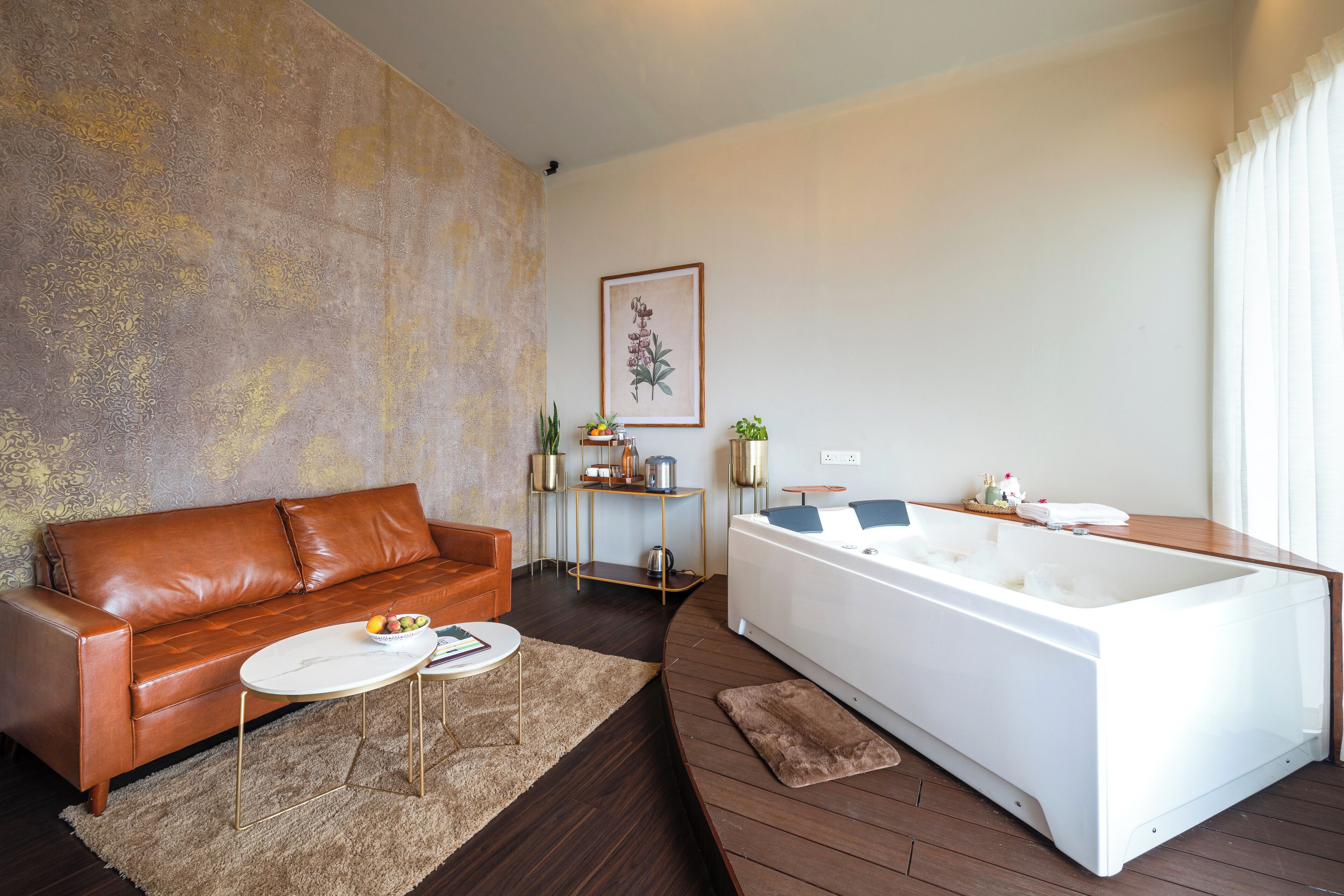A modern living room with a brown leather sofa, a white bathtub, and a small round table with a bowl of fruit.
