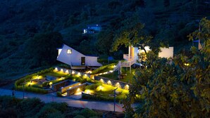 A modern house with a well-lit garden, surrounded by hills. - TOMORROWLAND  FARMS AND SUITES (Kodaikanal)
