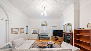 Una sala de estar con un sofá, un televisor, una chimenea y una estantería.