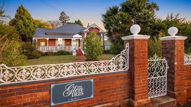 Una casa de ladrillo con una cerca blanca y un letrero que dice 'The Glen Iris'.