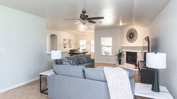A living room with a gray sofa, a ceiling fan, a fireplace, and a dining area in the background. - 4 Bedroom, 2 Bath in Midlothian! Centrally Located, Pet Friendly, Close to Local Wedding Venues. (Midlothian)
