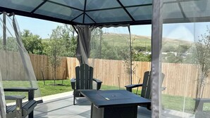 An outdoor patio with a covered seating area, a table, and chairs.