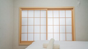 A room with a bed, a window with a wooden frame, and a wall socket. - Miyu Bonichi (Osaka)