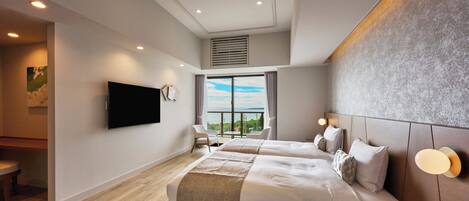 Een moderne hotelkamer met twee bedden, een flatscreen-tv, een balkon met uitzicht en een bureau met lamp.
