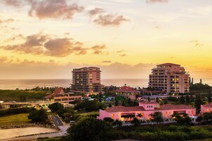 A coastal hotel complex with multiple buildings, including a prominent tower and several smaller structures.