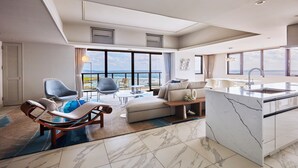 A modern living area with a view of the sea, a marble floor, and a kitchen with a marble island. - Hotel Shigira Mirage Beach Front (Miyakojima)