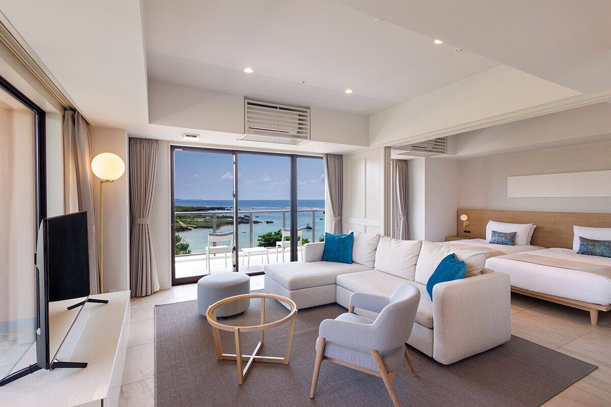 Une chambre d’hôtel moderne dotée d’un grand balcon, d’un canapé, d’un lit et d’une télévision.