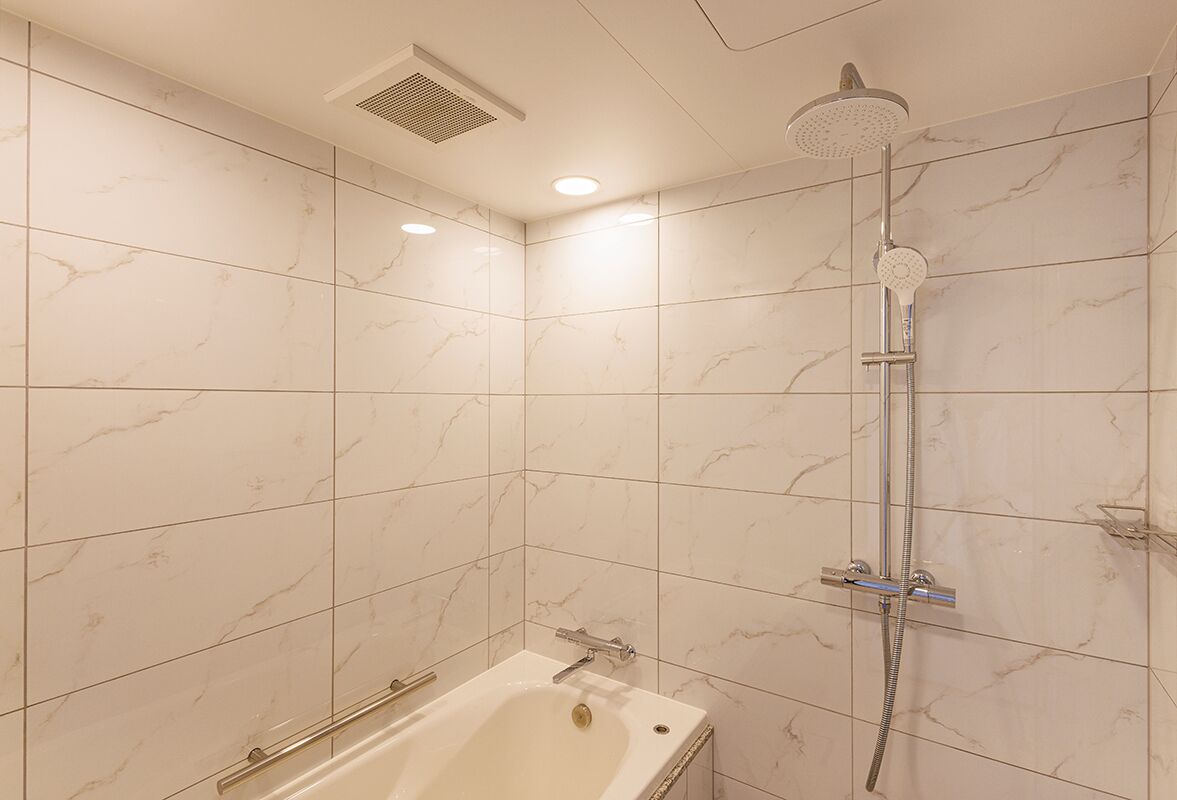 A bathroom with a bathtub, a shower with a handheld showerhead, and a wall-mounted toilet.