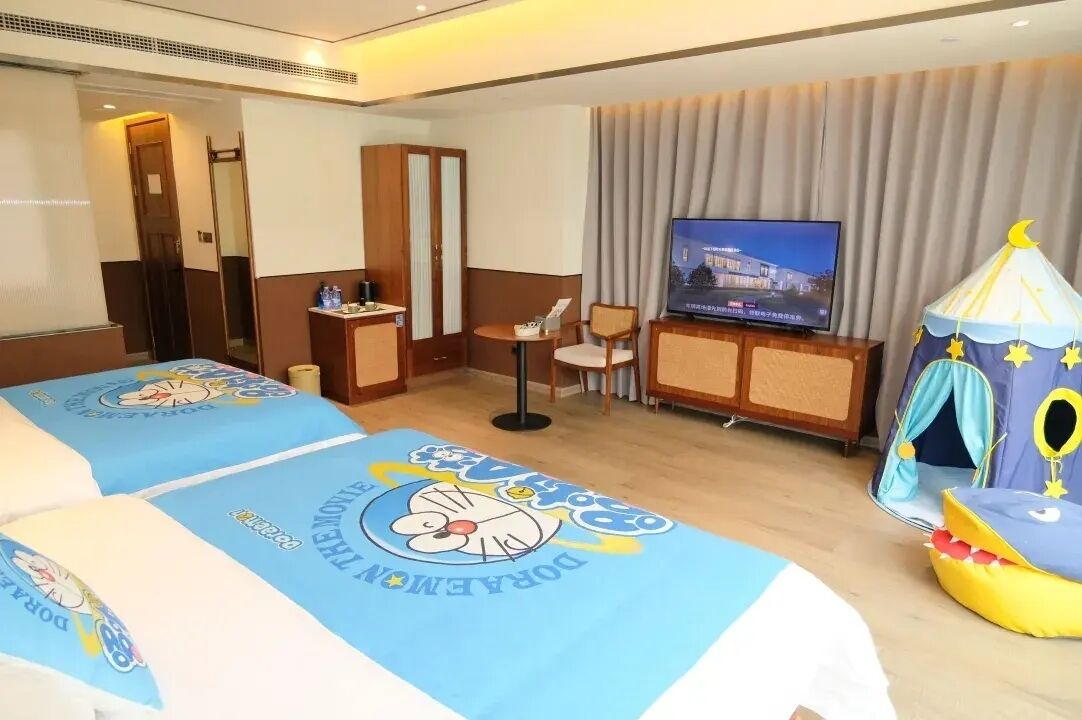 Une chambre d’hôtel avec deux lits, une télévision, une petite table, une chaise, une armoire et une décoration rappelant une tente.