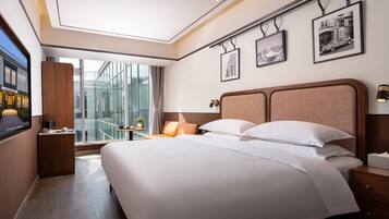 Una habitación de hotel moderna con una cama grande, una mesita de noche y cuadros enmarcados en la pared.